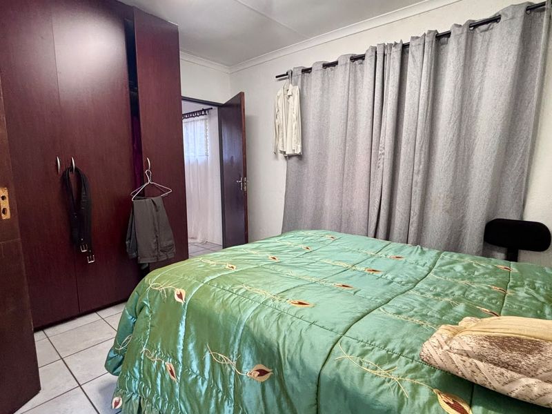 A bedroom featuring tiled flooring, a built-in wardrobe, and coved ceiling details, offering a functional space with potential for modernization.
