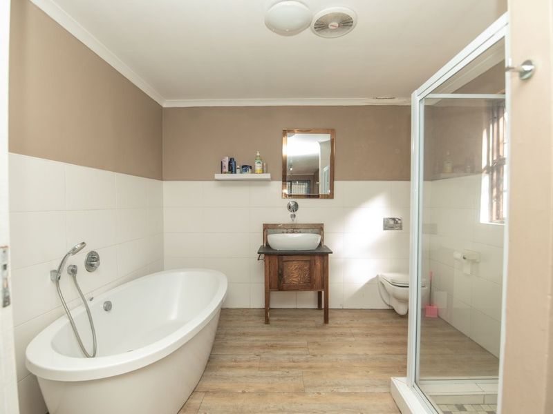 A functional bathroom featuring a freestanding bathtub, a separate shower enclosure, a wall-mounted toilet, and a wooden vanity with a vessel sink.