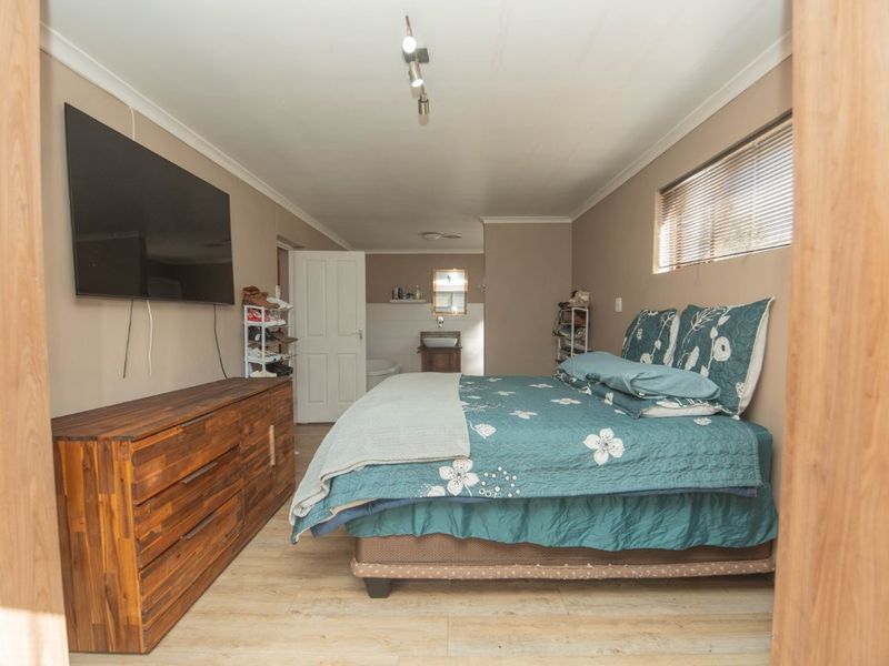 A bedroom featuring laminate flooring, venetian blinds, and direct access to an en-suite bathroom area.