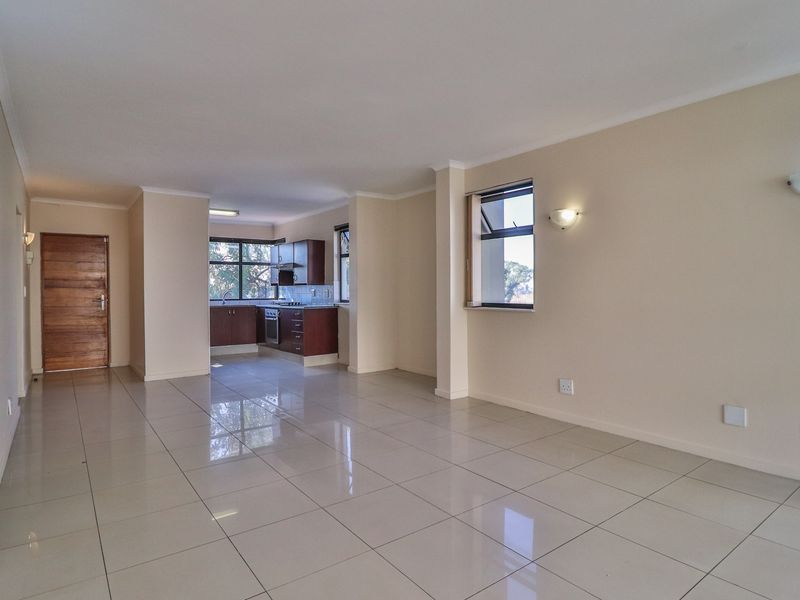 Spacious open-plan living area featuring tiled floors and a functional kitchen with built-in cabinetry, oven, and hob.