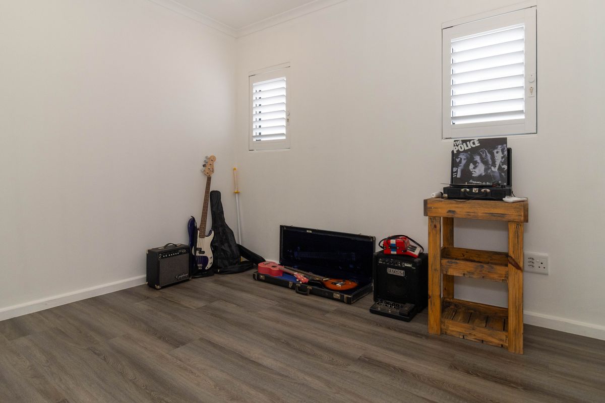 A clean, neutral bedroom featuring modern laminate flooring and white plantation shutters, offering a versatile space ready for personalization.