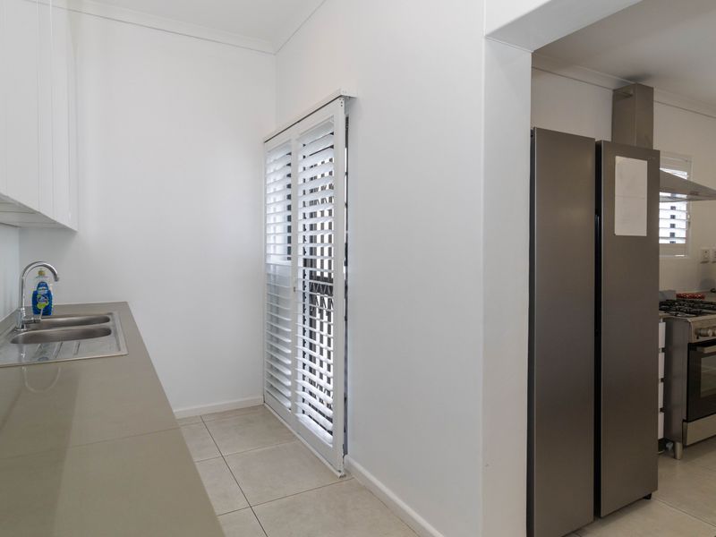Modern kitchen featuring stone countertops, double bowl sink, stainless steel appliances including a gas hob and extractor fan, and tiled flooring.