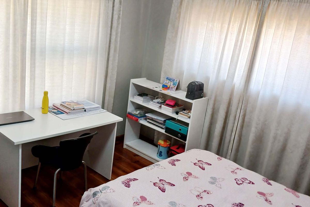 A functional bedroom featuring timber flooring and dual window treatments, providing a comfortable space with natural light.