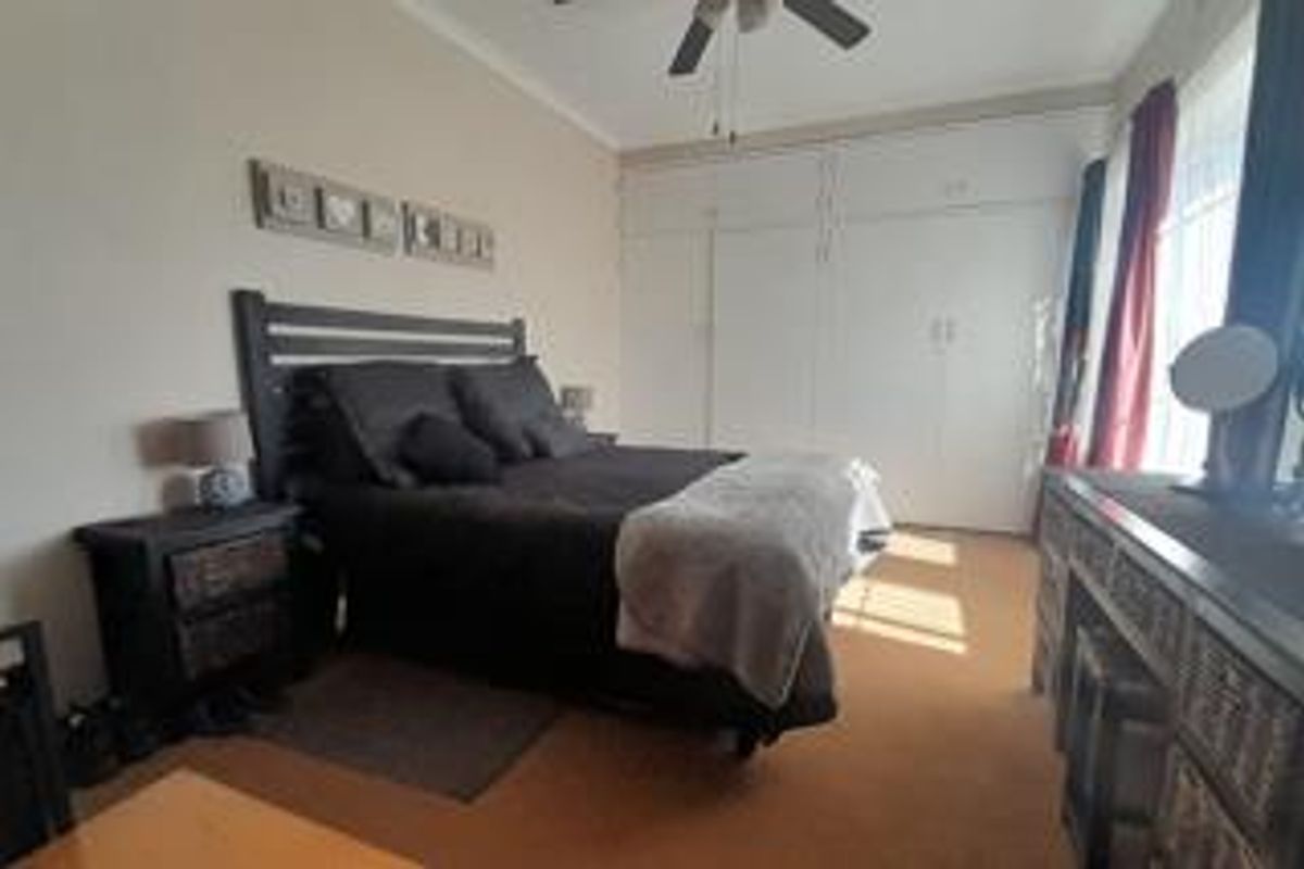 A bedroom featuring built-in cupboards and a ceiling fan, offering a functional space with neutral wall finishes.