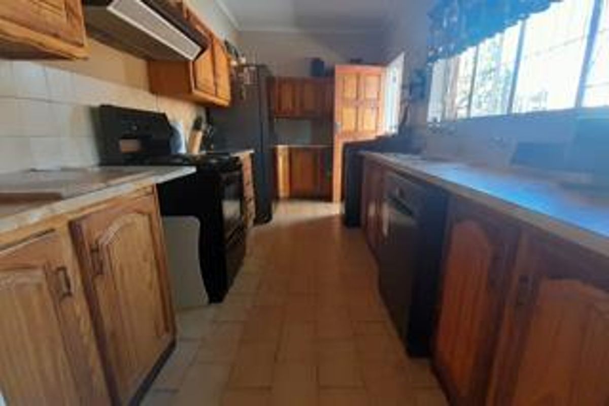 A dated kitchen featuring wooden cabinetry, tiled flooring, and built-in appliances, offering significant potential for a modern renovation.