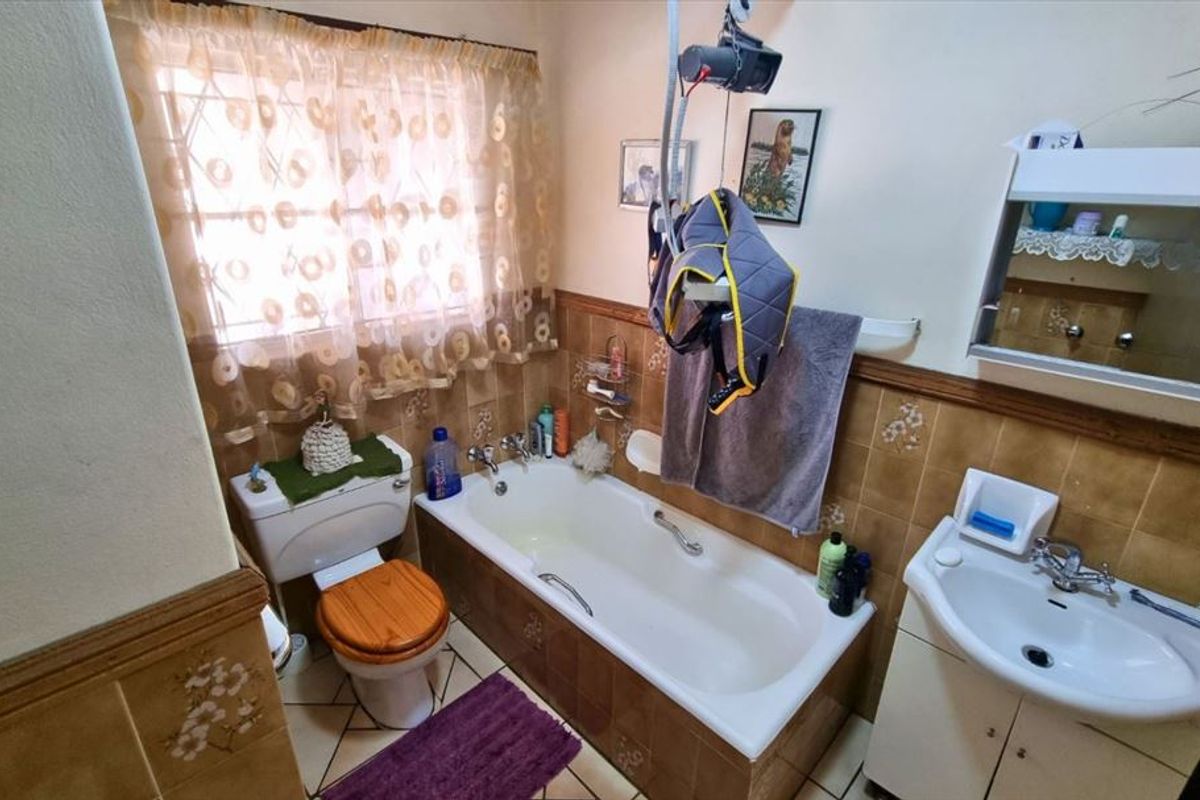 A dated bathroom featuring a standard bathtub, toilet, and pedestal sink with traditional wall tiling and a medicine cabinet.