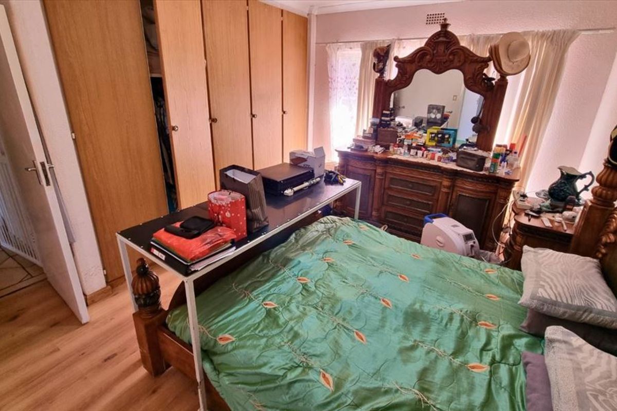 A bedroom featuring laminate flooring and built-in wooden cupboards, offering a functional space with potential for modernization.