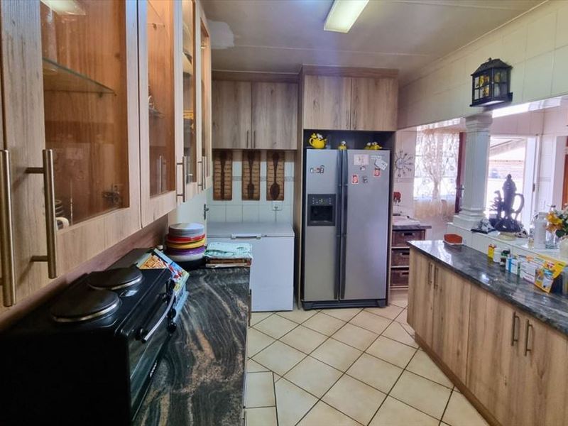 A functional kitchen featuring wood-look cabinetry, granite countertops, and ceramic tiled flooring, offering ample storage and workspace for daily meal preparation.