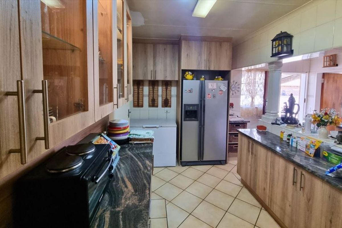 A functional kitchen featuring wood-look cabinetry, granite countertops, and ceramic tiled flooring, offering ample storage and workspace for daily meal preparation.