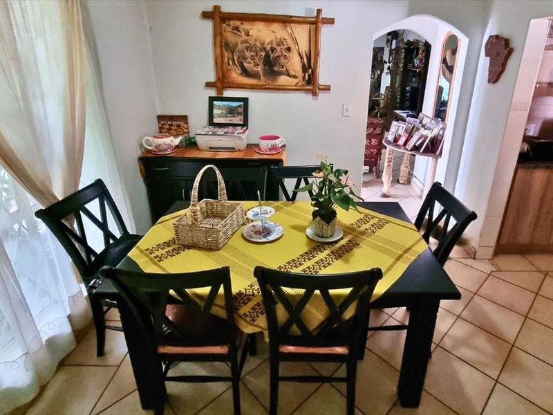 A dining area featuring tiled flooring and an arched entryway leading into the adjacent kitchen space.