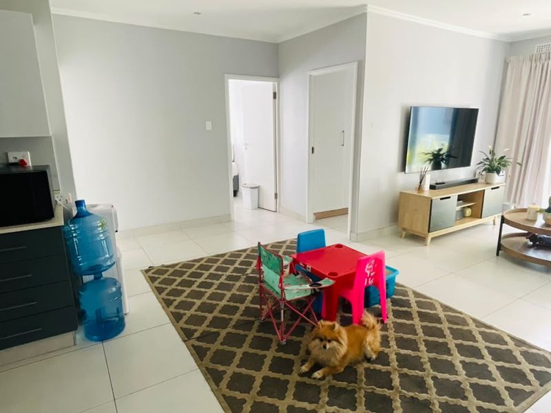 Open plan living area featuring neutral walls, tiled flooring, and recessed downlights, providing a bright and versatile space for daily living.