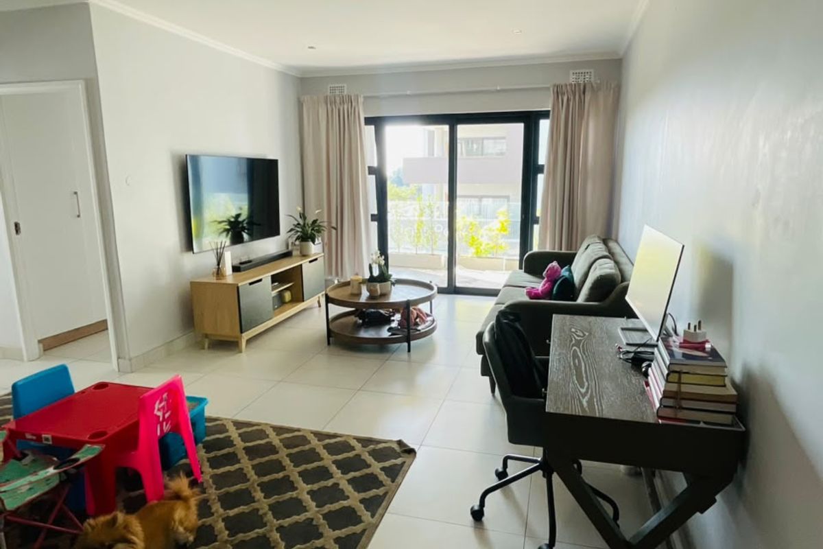 A bright, open-plan living area featuring large sliding glass doors that provide access to a balcony and allow for ample natural light.
