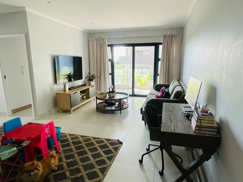 A bright, open-plan living area featuring large sliding glass doors that provide access to a balcony and allow for ample natural light.