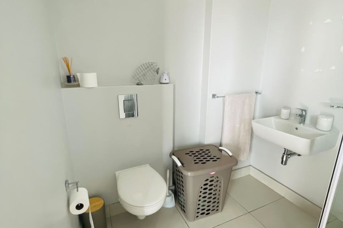 A clean and modern bathroom featuring a wall-hung toilet with a concealed cistern, a wall-mounted basin, and tiled flooring.
