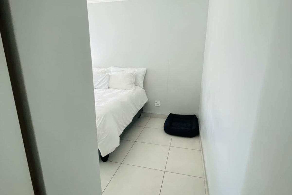 A view into a bedroom featuring neutral wall paint, tiled flooring, and coved ceiling details.