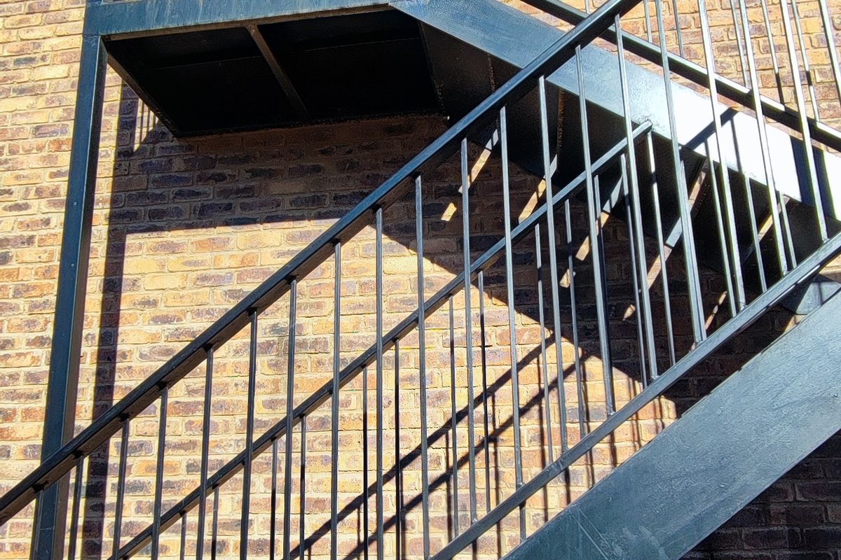 Exterior view of a brick apartment building featuring a functional metal staircase and balcony access.