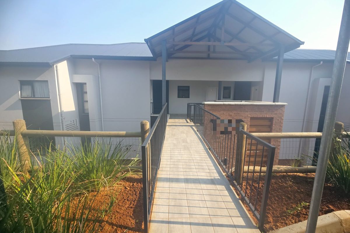 A modern apartment complex entrance featuring a tiled walkway, metal railings, and a covered entryway with brick detailing.