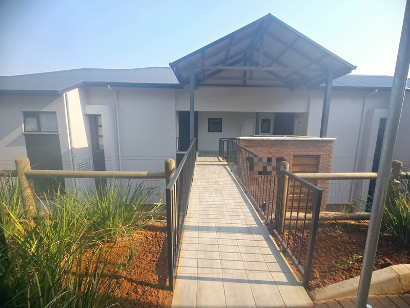 A modern apartment complex entrance featuring a tiled walkway, metal railings, and a covered entryway with brick detailing.