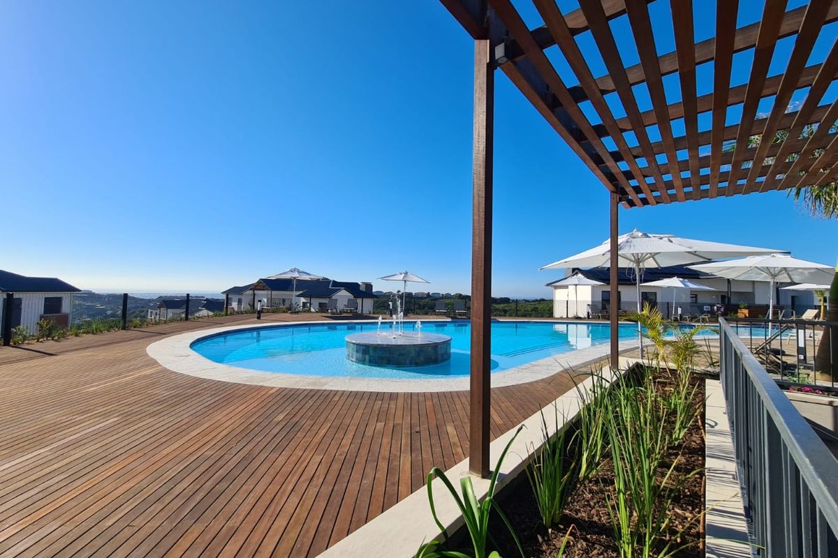 A well-maintained outdoor pool area featuring timber decking, a central water fountain, and a wooden pergola, offering a pleasant recreational space.