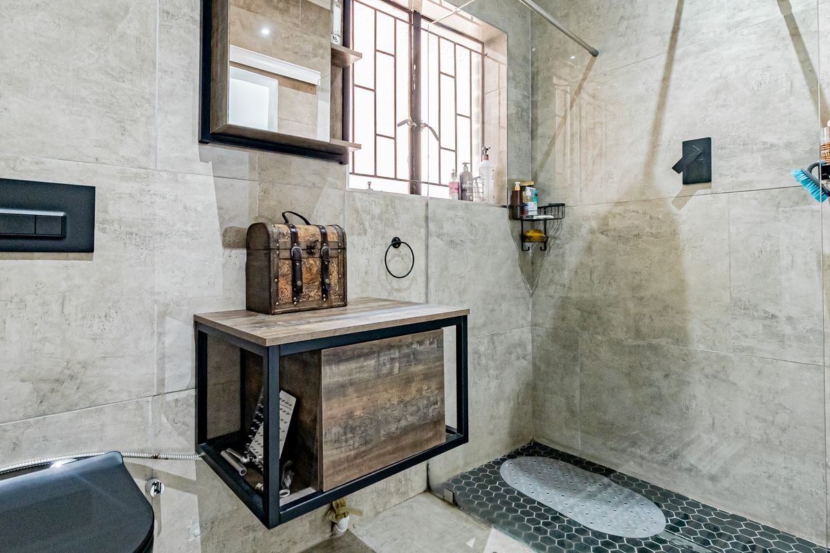 Modern bathroom featuring a wall-mounted vanity, walk-in shower with dark hexagonal floor tiles, and neutral wall tiling with a concealed cistern toilet.