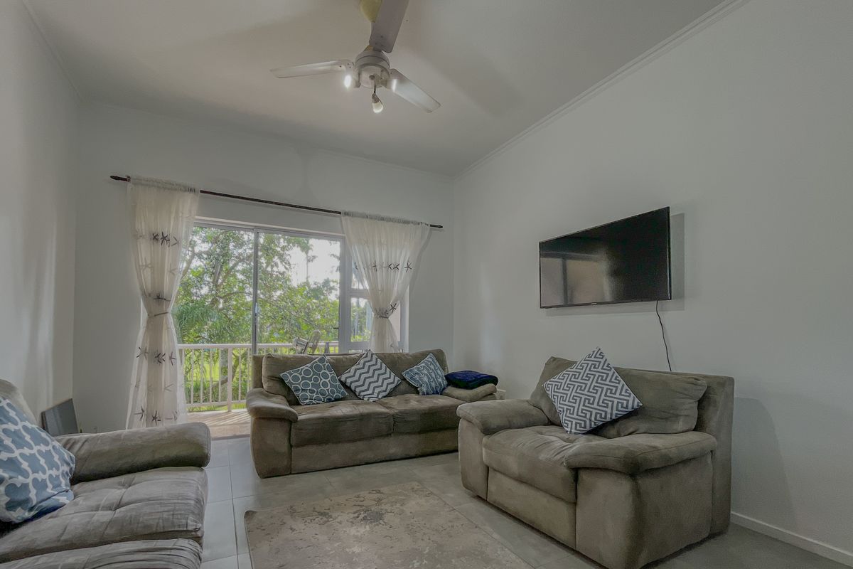 A living room featuring tiled flooring, a ceiling fan, and a sliding glass door providing access to an outdoor balcony area.