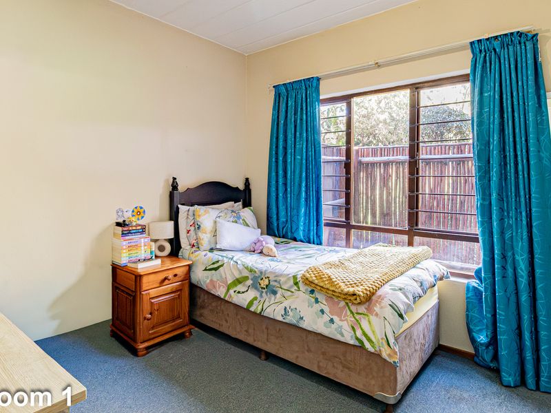 A functional bedroom featuring carpeted flooring and a large window that allows for natural light.