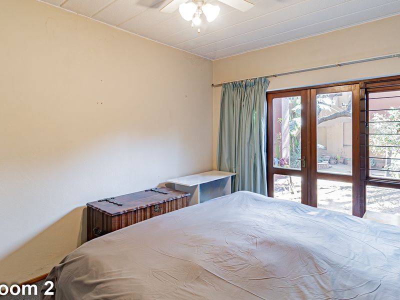 Bedroom featuring a ceiling fan and timber-framed glass doors providing direct access to the outdoor area.