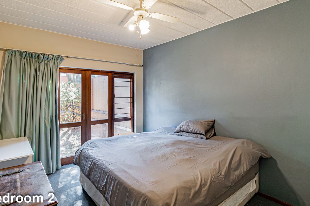 A bedroom featuring a ceiling fan, carpeted flooring, and a wooden framed glass door providing access to the exterior.