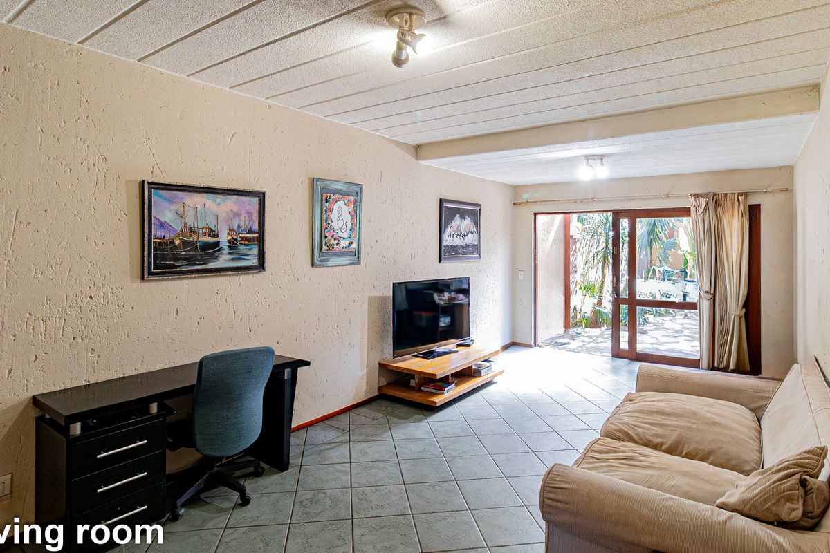 A living room featuring tiled flooring, textured walls, and a sliding glass door providing access to an outdoor area.