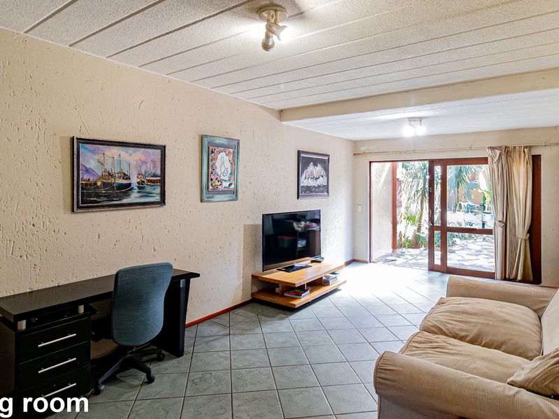 A living room featuring tiled flooring, textured walls, and a sliding glass door providing access to an outdoor area.