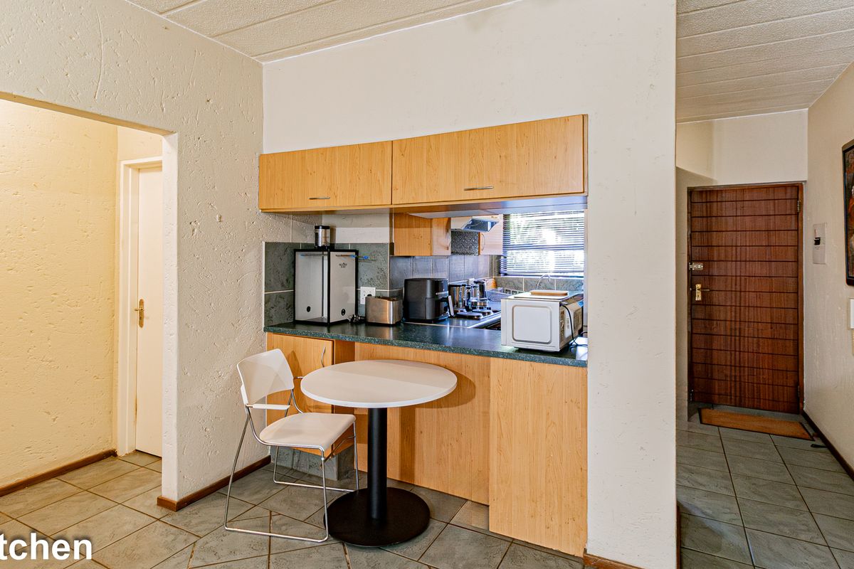 Compact kitchen featuring laminate cabinetry, tiled backsplash, and ceramic flooring, offering a functional layout with integrated cooking appliances.