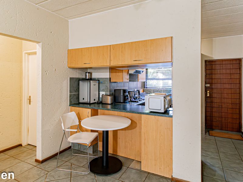 Compact kitchen featuring laminate cabinetry, tiled backsplash, and ceramic flooring, offering a functional layout with integrated cooking appliances.