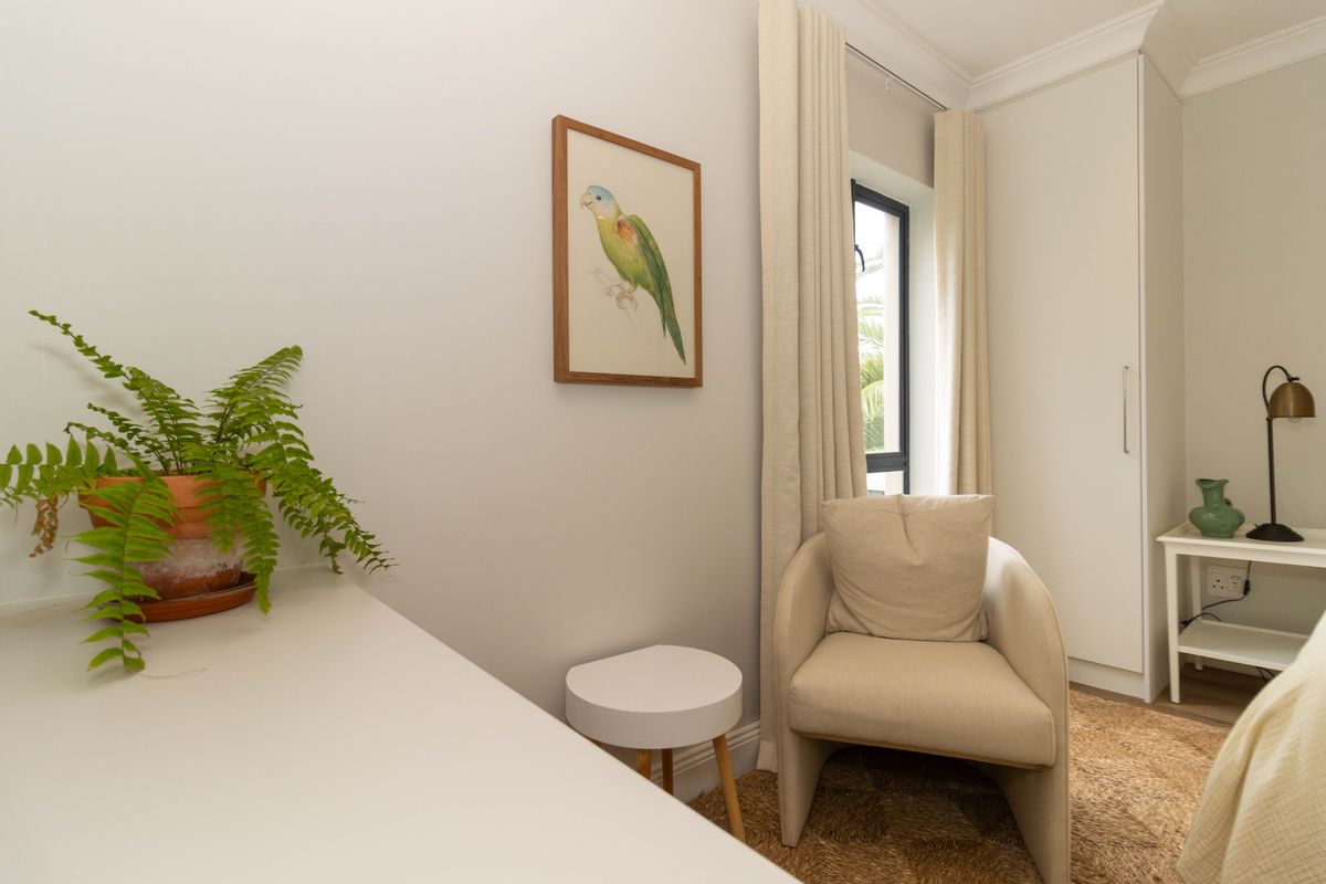 A well-maintained bedroom featuring a built-in wardrobe, neutral wall finishes, and a window with curtains.
