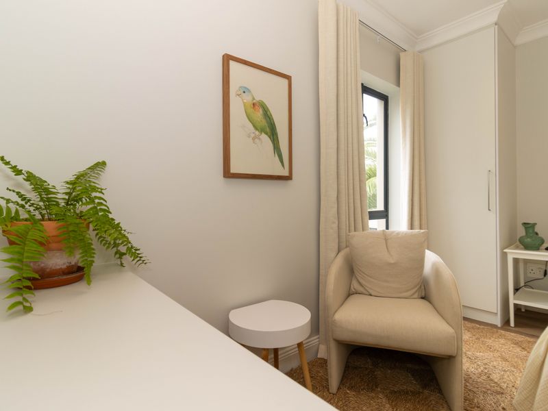 A well-maintained bedroom featuring a built-in wardrobe, neutral wall finishes, and a window with curtains.
