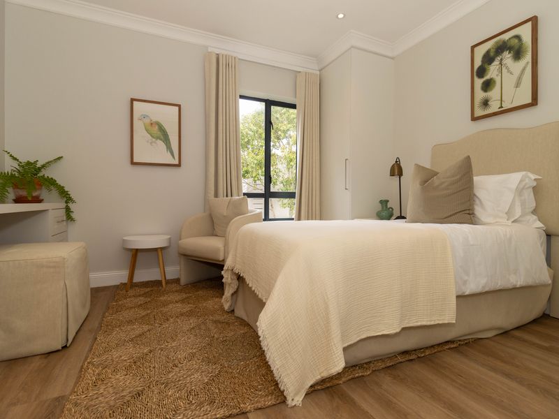 A well-maintained bedroom featuring laminate flooring, built-in wardrobe storage, and neutral finishes with recessed lighting.
