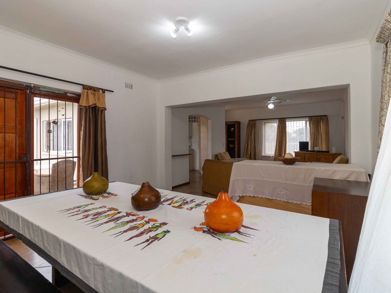 Open plan living and dining area featuring neutral finishes, ceiling fan, and direct access to an outdoor patio through a security gate.