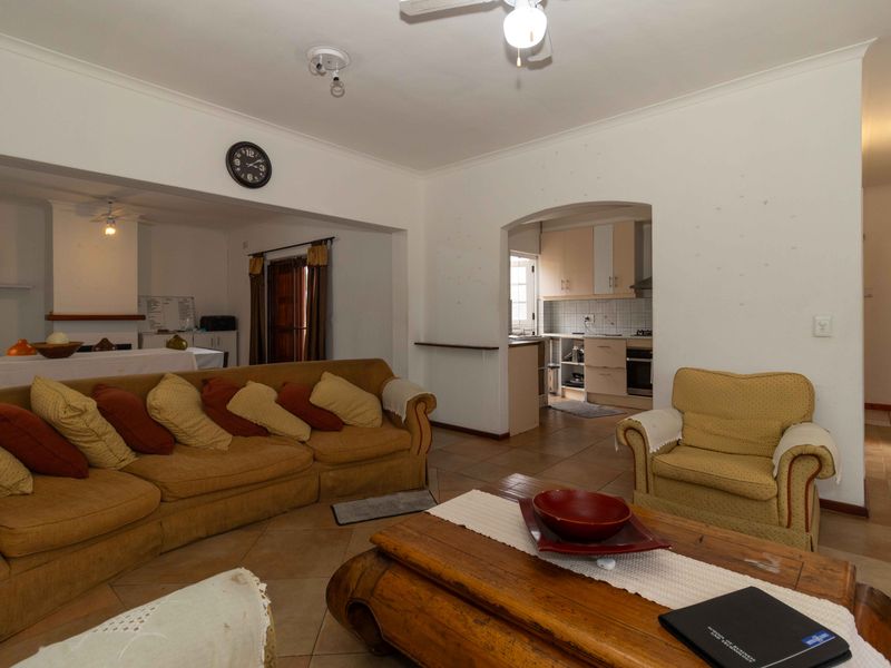 Open plan living area featuring tiled floors and an archway leading to a functional kitchen with built-in cabinetry and appliances.