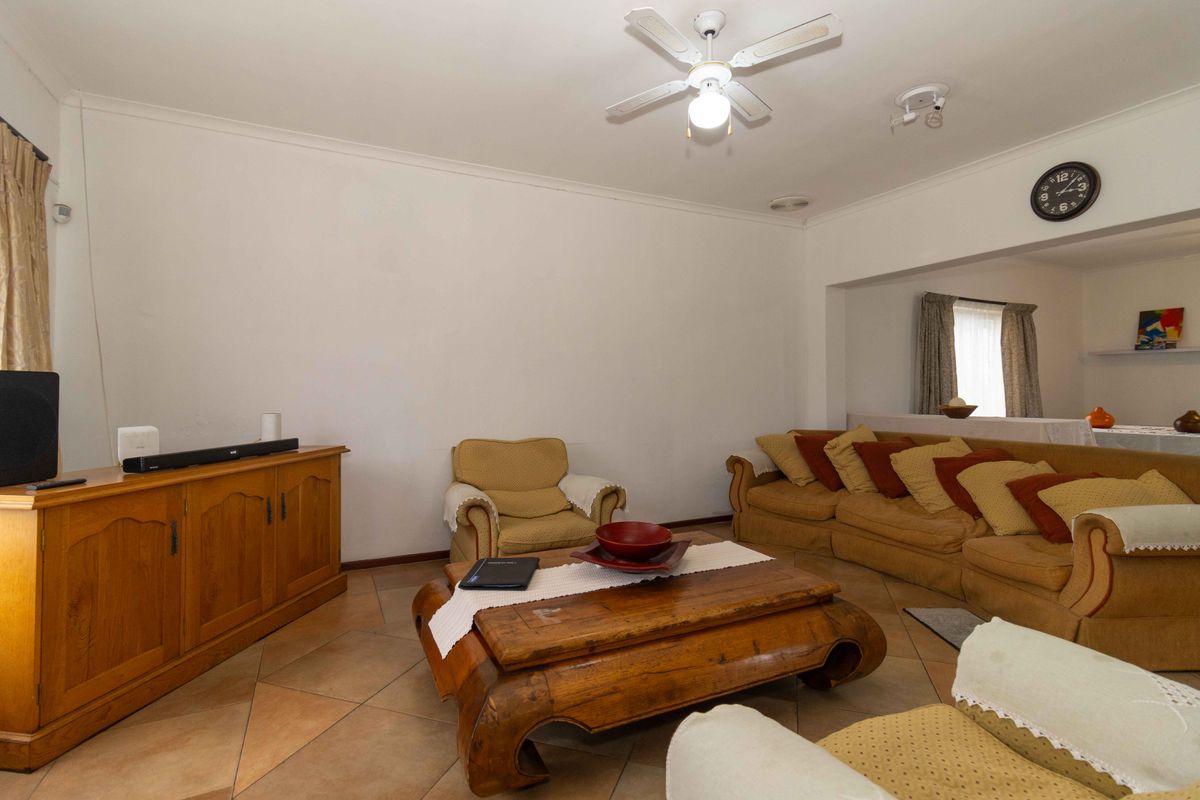A spacious living room featuring tiled flooring, a ceiling fan, and neutral walls, offering a comfortable and functional living space.