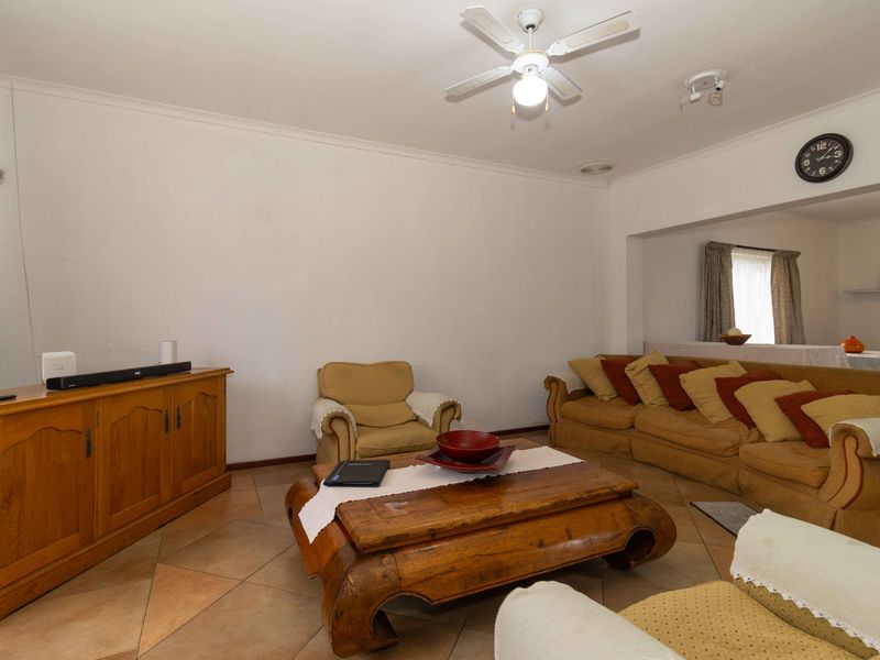 A spacious living room featuring tiled flooring, a ceiling fan, and neutral walls, offering a comfortable and functional living space.