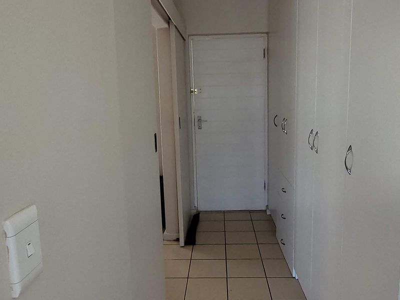 A functional hallway featuring neutral tiled flooring and extensive built-in cupboard storage, providing a clean and organized transition space within the apartment.