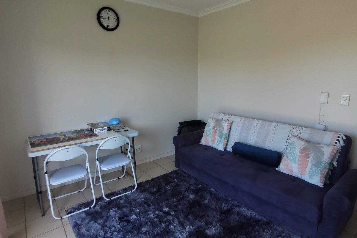 A functional living room area featuring tiled flooring and neutral wall finishes, providing a versatile space for relaxation or home office use.
