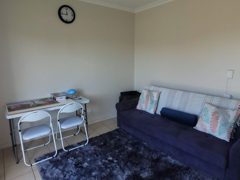 A functional living room area featuring tiled flooring and neutral wall finishes, providing a versatile space for relaxation or home office use.