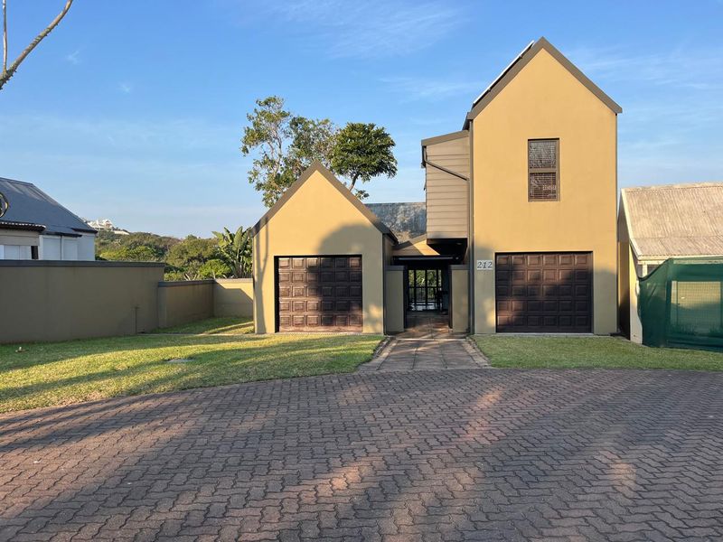 Front elevation of a two-story residential property featuring a double garage, paved driveway, and a landscaped front lawn.