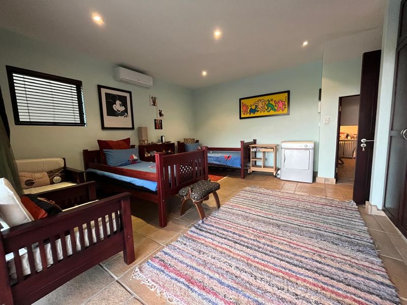 A spacious bedroom featuring tiled flooring, recessed downlighting, and a wall-mounted split-system air conditioner.