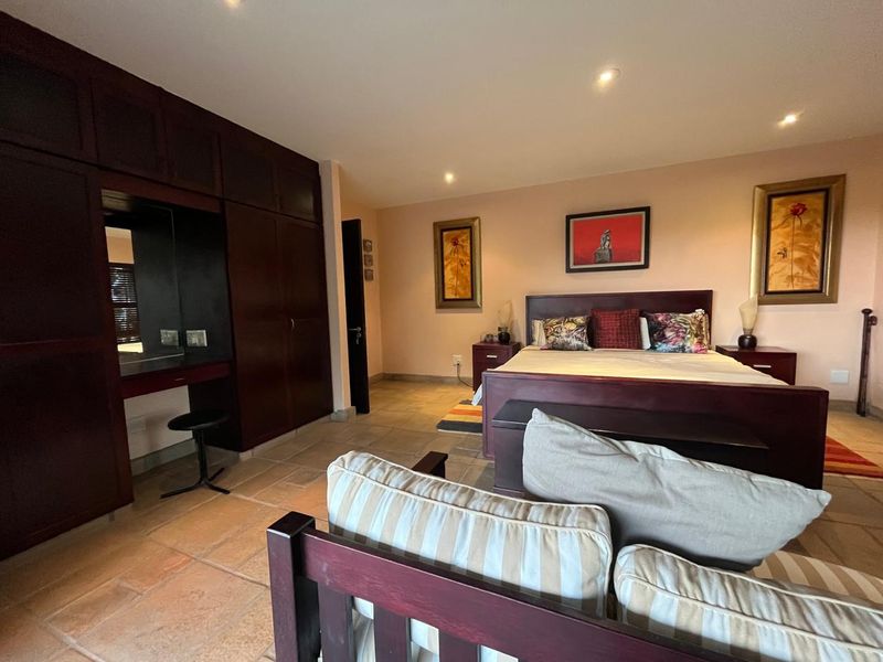 Spacious bedroom featuring built-in dark wood cabinetry, tiled flooring, and recessed lighting, offering a functional layout with ample storage space.