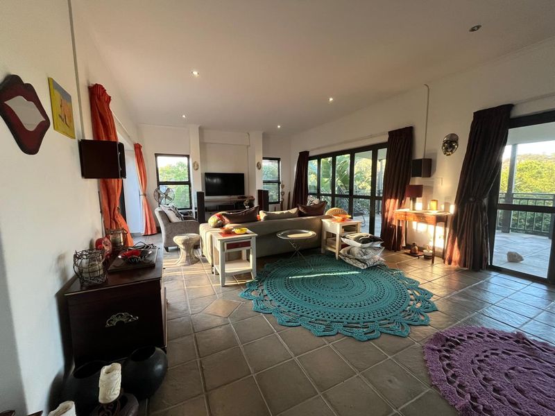 Spacious living room featuring large sliding glass doors that open to an outdoor area, tiled flooring, and recessed lighting.