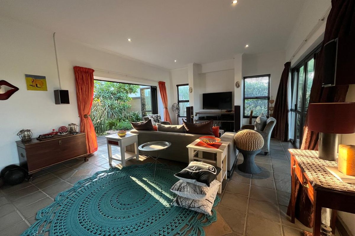 Spacious living room featuring tiled flooring, recessed lighting, and large sliding glass doors that provide seamless access to the outdoor garden area.
