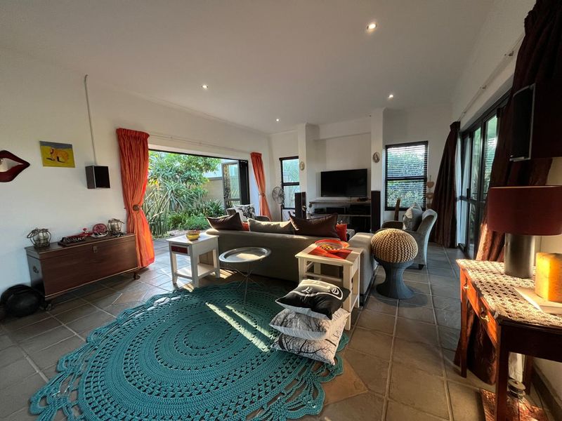 Spacious living room featuring tiled flooring, recessed lighting, and large sliding glass doors that provide seamless access to the outdoor garden area.