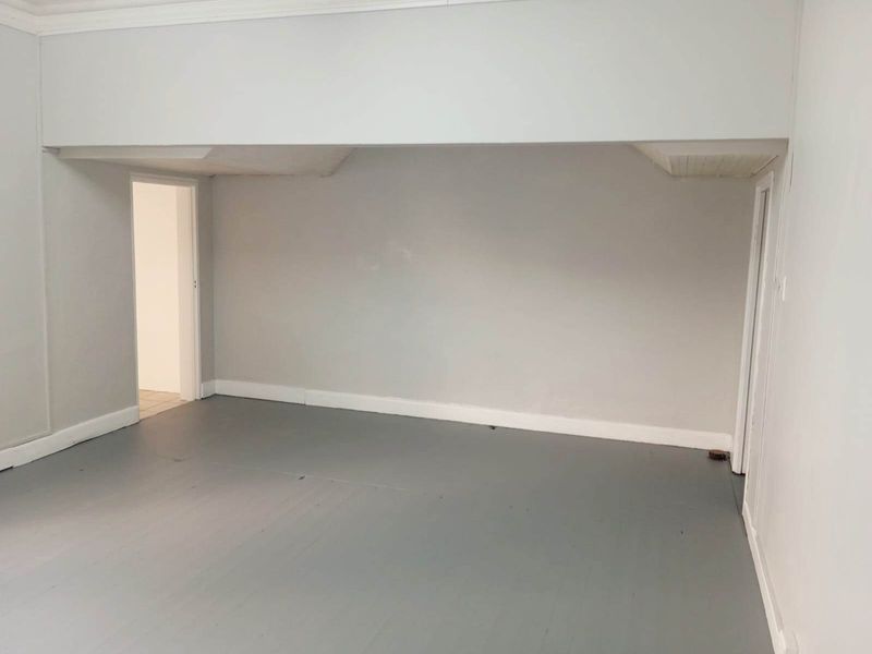 An empty, neutral-toned living area featuring painted timber flooring and clean architectural lines, ready for personalization and staging.