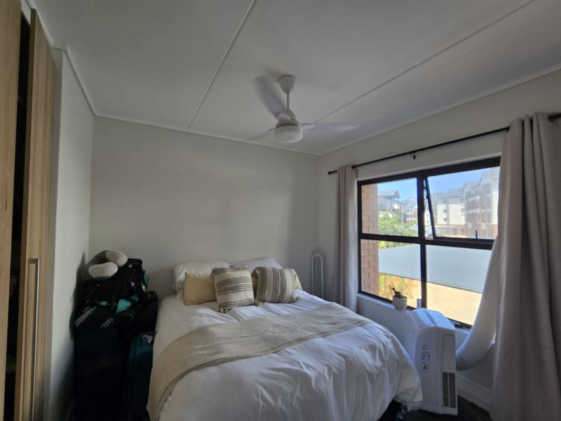 A bedroom featuring a ceiling fan, built-in wardrobe, and large window with natural light.